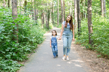 Obraz premium Family, nature, children concept - Mother and her little daughter spend time together on a walk in the park in summer