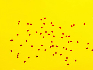Festive yellow background with spangles in the shape of heart. 