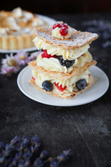 Tea and sweets on a dark background, Mille-feuille, Eclairs, Tart, Decorative with flowers, Selective focus, Closeup