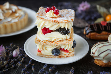 Tea and sweets on a dark background, Mille-feuille, Eclairs, Tart, Decorative with flowers, Selective focus, Closeup