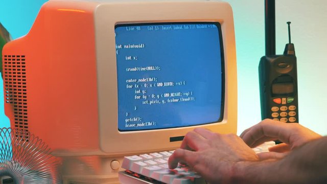 Using a vintage computer from the late 80s early 90s to work on a desk. Retro screen and background.