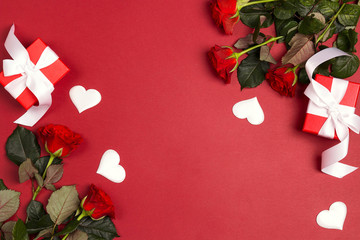 Rose flowers, gift box and decorative hearts on red  background. Place for text, top down composition.
