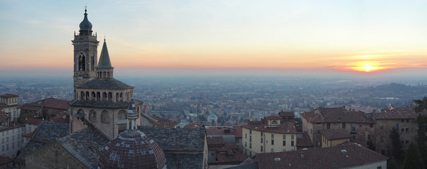 Fototapeta na wymiar Bergamo, Italy. The old town. Aerial view of the Basilica of Santa Maria Maggiore during the sunset. In the background the Po plain