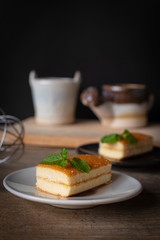 layer vanilla flavoured cake place on white plate on the wooden table there are black plate and