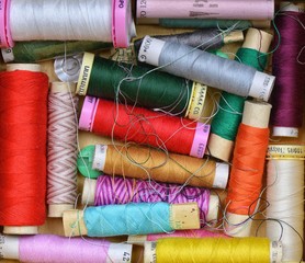 Several colored threads in the sewing basket.