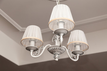 Chandeliers with three electric lamps and lampshades hanging on the ceiling. Concept cozy evening...