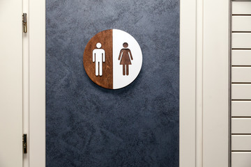 Toilet, wc icon, round wooden white and brown sign on restroom door in the hallway, restaurant, lobby. Concept sign of toilet room at airport, cafe, bar, hotel, train station