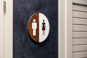 Toilet, wc icon, round wooden white and brown sign on restroom door in the hallway, restaurant, lobby. Concept sign of toilet room at airport, cafe, bar, hotel, train station
