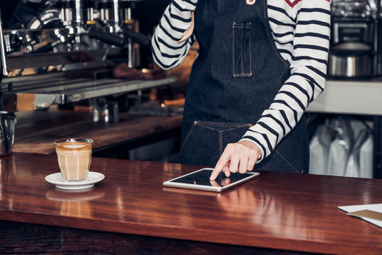woman barista take order by mobile and tablet,asia female waitress using digital device in coffee shop business at counter bar in cafe,modern food owner business start up