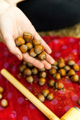 Young adult female holding hazelnuts above meal preparation.