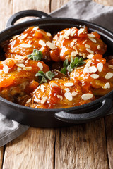 Gourmet food glazed chicken thighs with dried apricots and almond flakes close-up on the table. vertical