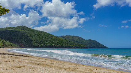 Fototapeta na wymiar Ein tropischer Strand mit Bergen und Baum in der Karibik Punta Cana, Atlantik, nördlich des Äquators