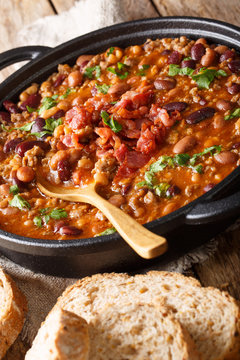 American cowboy beans with ground beef, bacon in a spicy sauce close-up. vertical