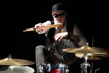 Fototapeta na wymiar Drummer with a drumsticks in his hands sits behind drum kit on the black background
