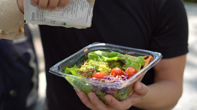 Putting Healthy Sunflower Seeds on Fresh Salad in Plastic Container