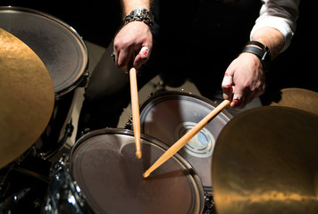Obraz premium Drummer with a drumsticks in his hands playing on drum set on stage on the black background 