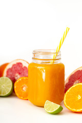 Freshly blended yellow and orange fruit smoothie in glass jar. Glass jar mugs with orange health smoothie, lime, grapefruit, lemon, tangerine. Selective focus. Copy space. Vegetarian food concept.  