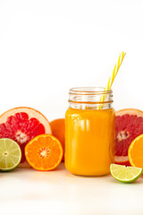 Freshly blended yellow and orange fruit smoothie in glass jar. Glass jar mugs with orange health smoothie, lime, grapefruit, lemon, tangerine. Selective focus. Copy space. Vegetarian food concept.  