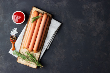 Raw frankfurter sausages with ketchup on cutting board. Top view. Copy space for text.