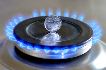 Gas hob with burning natural gas and Russian rouble coin