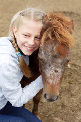 Pony and horsewoman - little girl hugging her best friend