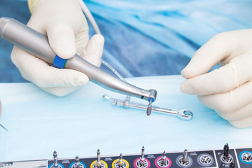 Close-up dental implant in the hands of a dentist. An implantation surgery is underway.