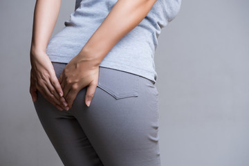 Woman suffering from hemorrhoids and hand holding her bottom because having Abdominal pain. Health care concept.