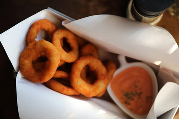 Onion rings with sauce on wooden table