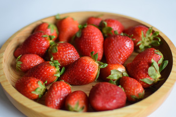 Fresh strawberries on wooden bowl. Village strawberry with wooden plate closeup.