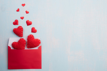 Valentines day and love concept. Red hearts splash out from red pink letter cover on blue sky wooden background.