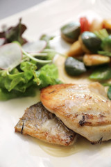 Sea bass fillet with grilled vegetables and salad on wooden table