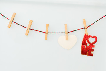 Pink hearts and word LOVE on rope with clothespins, on a white  background
