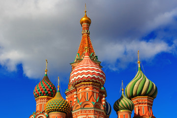 Fototapeta na wymiar Colored domes of St. Basil's Cathedral in Moscow against blue sky with clouds in sunny day