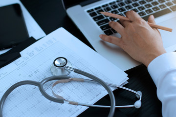 Medicine doctor. Stethoscope with heartbeat report and doctor analyzing checkup on laptop in health...
