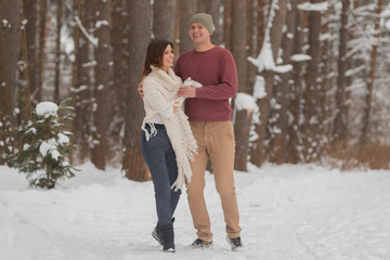 Fototapeta na wymiar Young couple on a romantic walk in the winter forest
