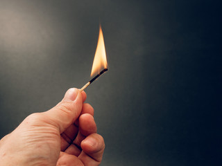 Match with a fire flame burning being held by a hand