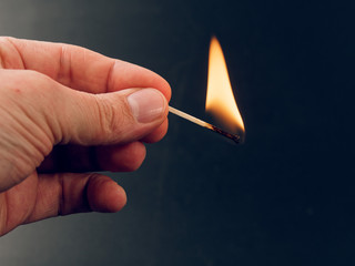 Match with a fire flame burning being held by a hand