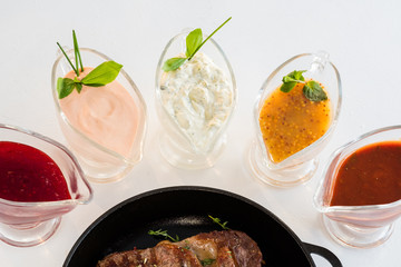 Restaurant food composition. Assorted sauce gravy boats. Roasted meat main course.