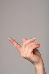 Soft contact lens on the finger of the female hand on a gray background