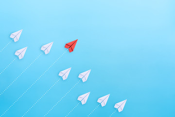Leadership concept with red paper plane leading among white on blue background with copy space