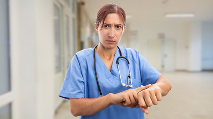 Angry nurse pointing at wrist.