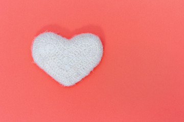 White flyffy knitted heart on paper background with copy space for text. Card for wishes with Valentine’s day, birthday.