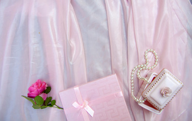 pink background with gift box and pearl beads and a rose, mother's day, symbols of love