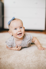 Little baby girl wearing bow crawling on a floor and smiling