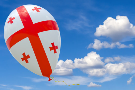 A balloon with the image of the national flag of Georgia is flying against the blue sky.