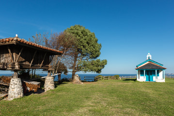 Typical granary (horreo) and the chapel of La Regalina in Cadavedo, Asturias, Spain