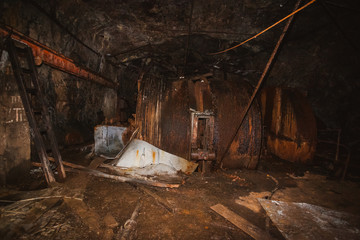 Fototapeta na wymiar Inside old closed coal mine; dangerous tunnels full of dirt, lots of abandoned rusty equipment, devastated industrial place