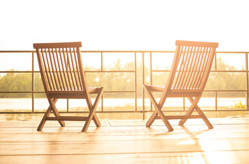 Balcony view at sunset with wooden chairs. Interior design of resort at holiday travel