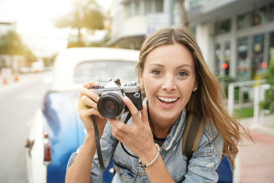 Attractive photographer taking photos with vintage camera in city
