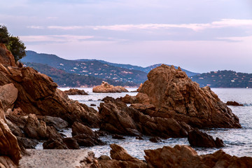 Fototapeta na wymiar Red cliffs, rocky coast of Esterel massif (St.Raphael - Agay), sunset sky. Cote d'Azur, French Riviera. Holidays in France.